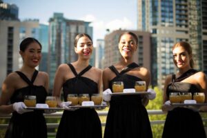 catering women in black dresses serving drinks and smiling