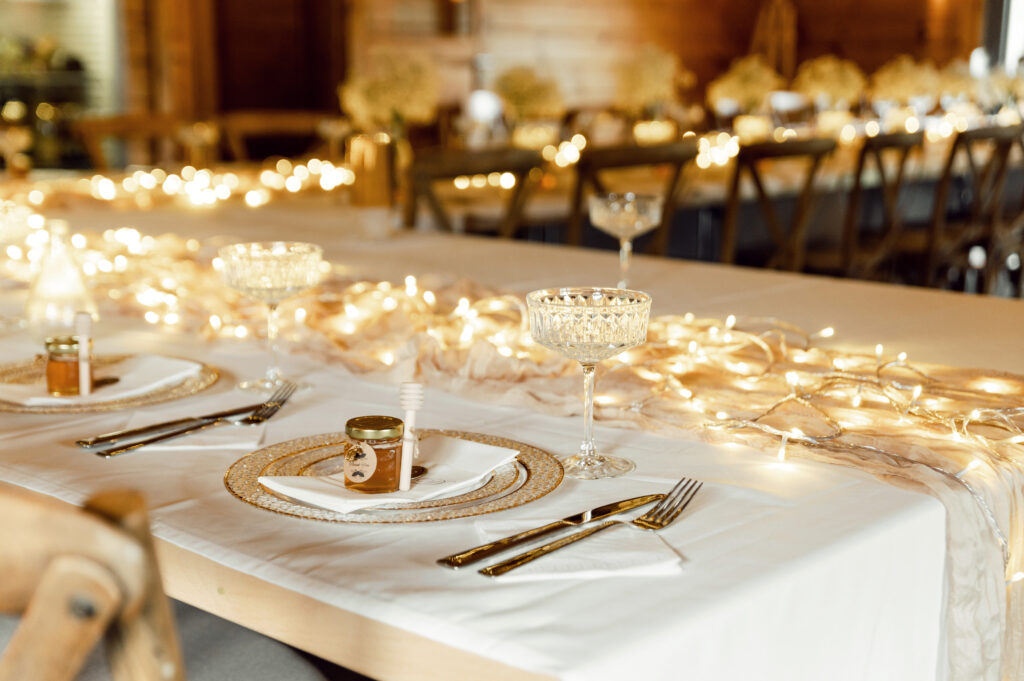 white linen table set with twinkle holiday lights for catering dinner event