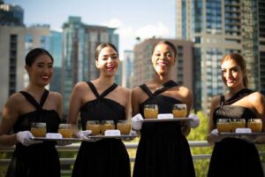 A group of servers holding serving trays with cocktails at a catered event in the DFW area.