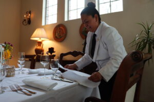 A server preparing napkins and cutlery for a gourmet catered event in Dallas, TX.