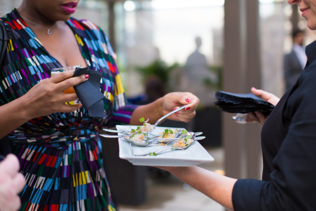 A woman samples an appetizer at a catered event in the DFW area.