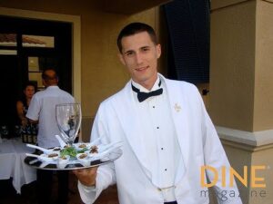 A server at Cater Dallas smiling and attending to guests