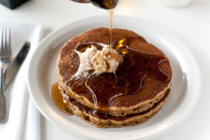 A stack of pancakes drizzled in maple syrup 