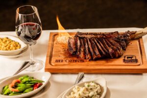 A savory steak plated with sides and a glass of wine from III Forks