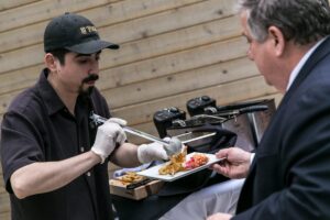 chef plating and handing dish to guest