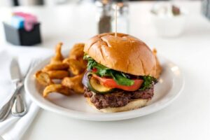 A plated burger with lettuce, tomatoes, and all the toppings for Luckys