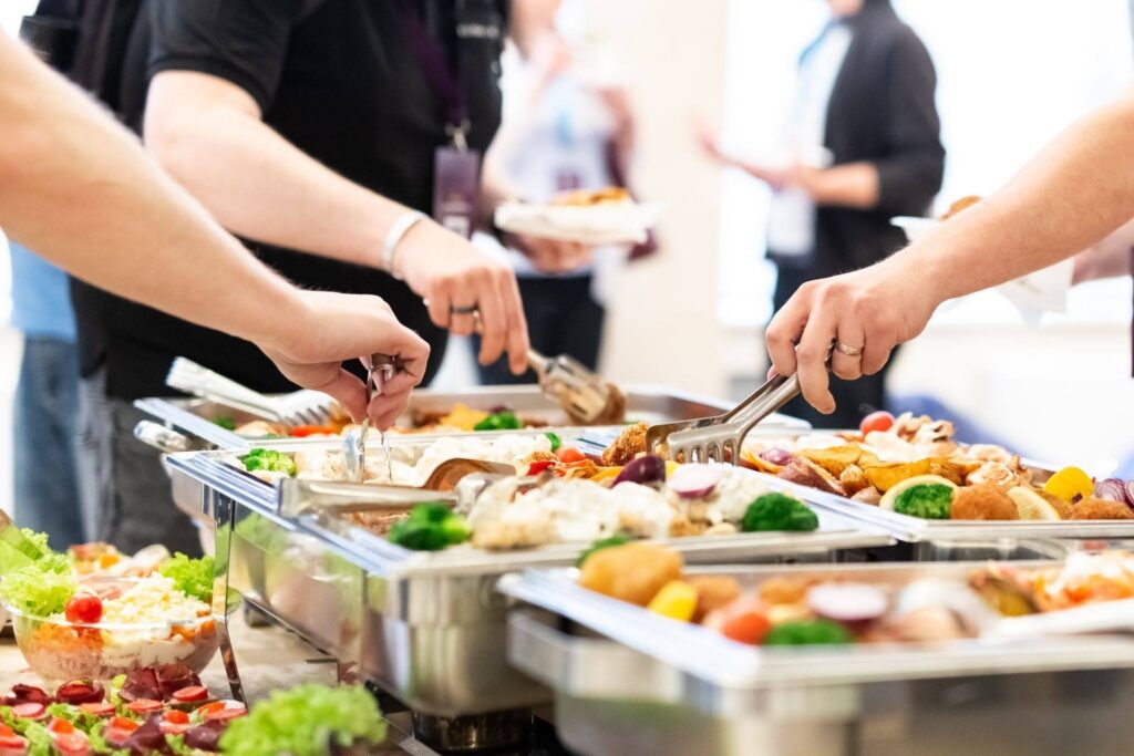 A photo of a catering set up with three people getting food during a break.