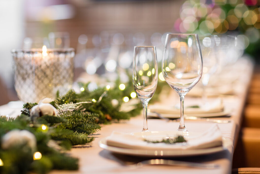 Christmas dinner feast. A decorated dining table with champagne glasses and christmas tree in background.